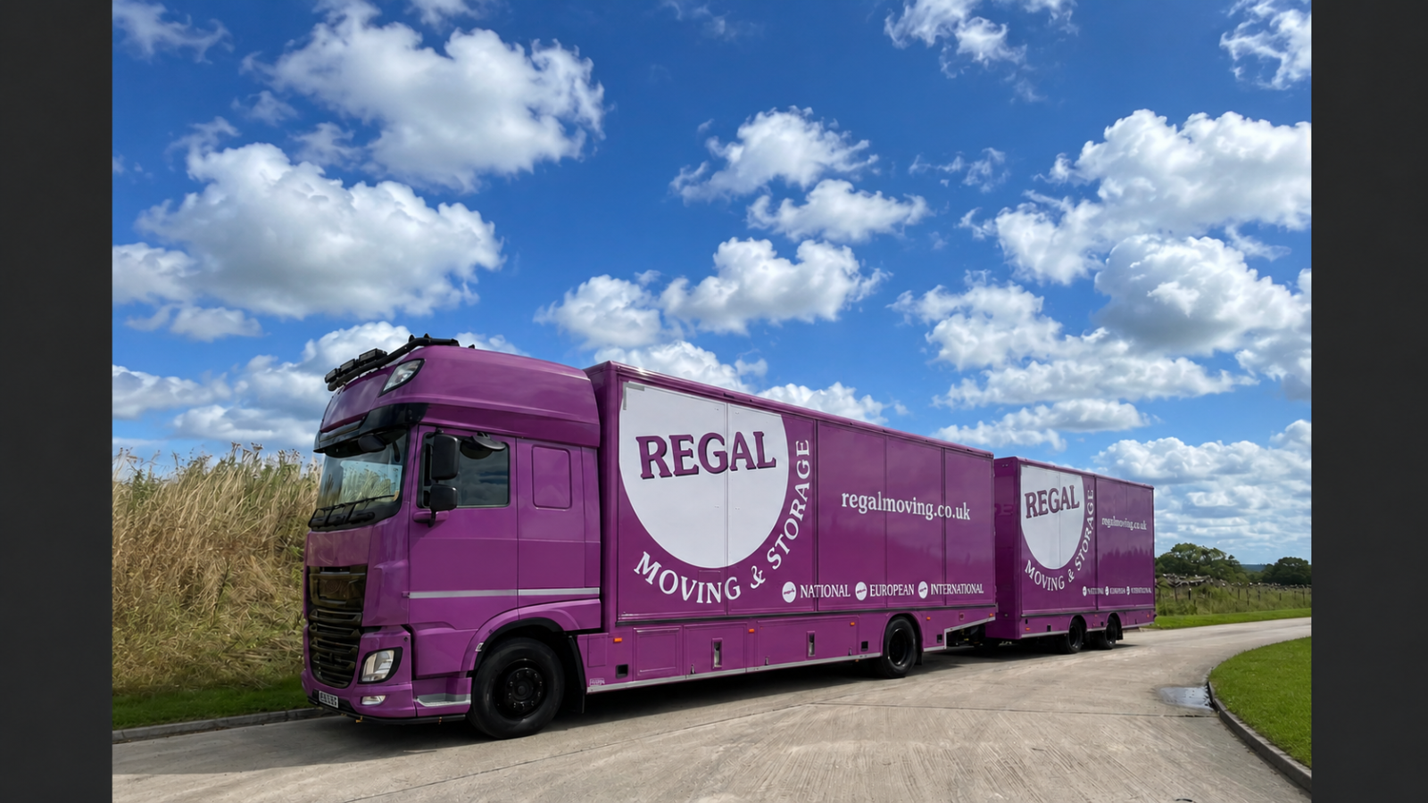 Purple Regal Moving & Storage truck and trailer on a countryside road