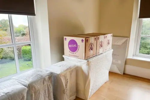 Neatly packed room with a Regal Moving & Storage box on top of covered furniture