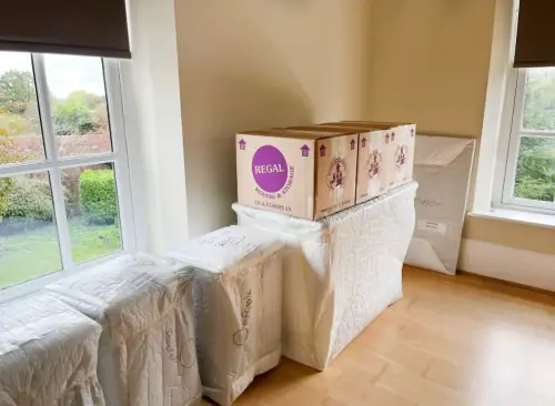Neatly packed room with a Regal Moving & Storage box on top of covered furniture